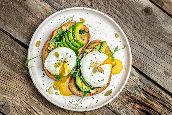 Ispanak, avokado ve balkabağı tohumlu haşlanmış yumurta sağlıklı yemek, keto diyeti, diyet öğle yemeği konsepti. Üst görünüm.