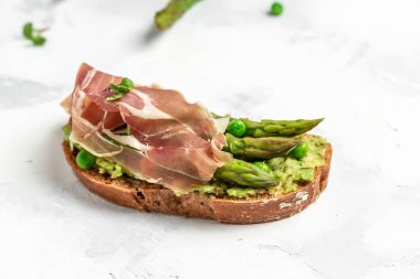 Avokado, kuşkonmaz, jambon, jambon ve jambonlu lezzetli tost. Sağlıklı yemek, diyet öğle yemeği konsepti, lezzetli kahvaltı veya atıştırmalık..