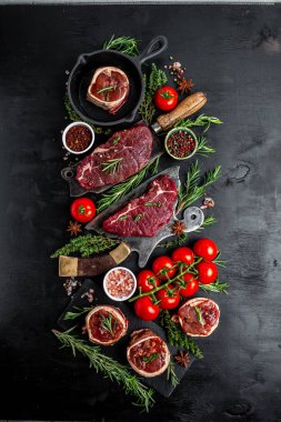 Çiğ et fileto Mignon bifteği üzerine biber ve tuz, fileminyon. Domuz pastırmasına sarılı sığır filetosu biftekleri ve koyu arkaplanda kekik. en üstteki görünüm.