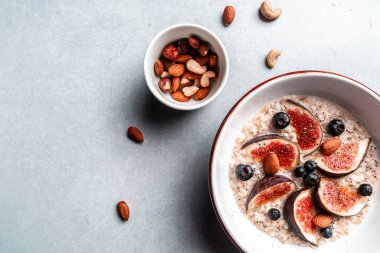 Lezzetli yulaf ezmesi, incir parçalarıyla süslenmiş, bir kasede çilek ve chia tohumları, sağlıklı kahvaltı glüten, laktozsuz, fitness yiyeceği. en üstteki görünüm.