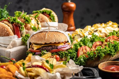Sosisli sandviç, hamburger, patates kızartması, ahşap arka planda ev yapımı hamburgerler. Fast food ve abur cubur kavramı,