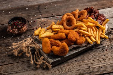 Fast food ürünlerini patates kızartması, nugget yemeği, abur cubur ve tahtadan yapılmış sağlıksız yiyeceklerle birlikte götür. afiş, menü, metin için tarif yeri.