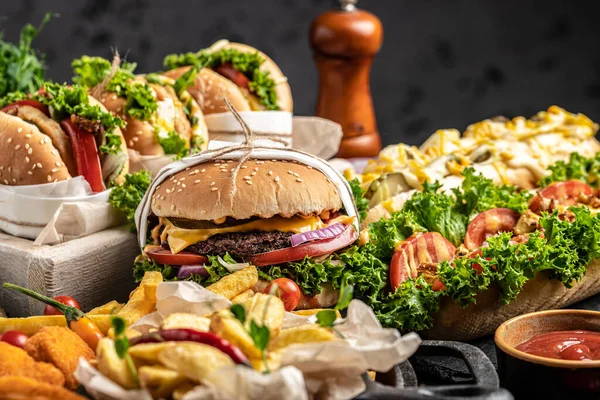 Sosisli sandviç, hamburger, patates kızartması, ahşap arka planda ev yapımı hamburgerler. Fast food ve abur cubur kavramı,