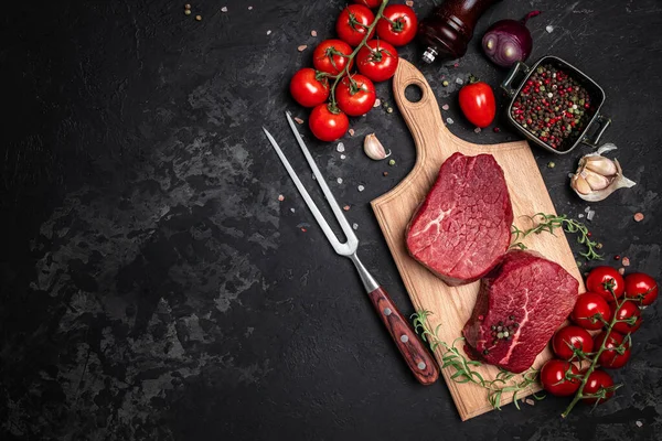 İki taze çiğ biftek ve arkaplanda pişmeye hazır baharatlar. Mutfak, yemek pişirme, konsept. afiş, menü, metin için tarif yeri, üst görünüm.