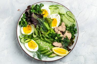 Ton balıklı vejetaryen Buda kâsesi avokado, yumurta, salatalık ve hafif arkaplanda taze salata. en üstteki görünüm.