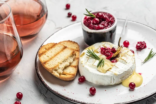 French cuisine. Baked camembert cheese with cranberries and basil leaves, wine on a light background, banner, menu, recipe place for text.