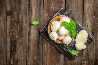Geleneksel mozzarella peyniri. Koyu ahşap arka planda taze fesleğen yaprakları. afiş, menü, metin için tarif yeri, üst görünüm.