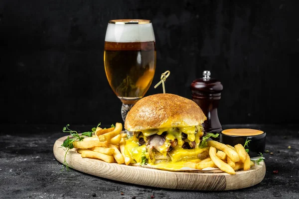 Tasty big burger and beer glass on wood tray. American food concept. fast food meal. banner, menu, recipe, place for text.