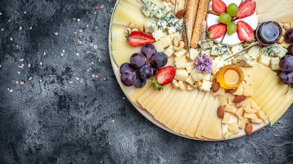 Cheese variety board or platter with cheese assortment, grapes, honey and nuts. aperitivo party concept, banner, menu, recipe place for text.