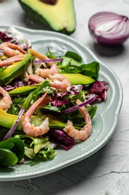 Taze avokado salatası, karides, marul yeşili karışım ve zeytinyağı, limon sosu. Sağlıklı yemek, lezzetli kahvaltı ya da atıştırmalık, dikey görüntü. en üstteki görünüm.