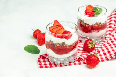 Taze meyve, yoğurt ve beyaz masada granola, cam kavanoz. Sağlıklı kahvaltı. Uzun afiş biçimi. en üstteki görünüm.