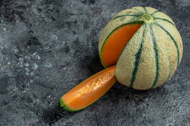 Tam ve dilimlenmiş Japon kavunları ya da koyu arkaplanda kavun. metin için yer.