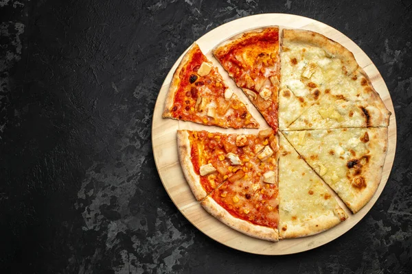 Tasty hawaiian pizza with chicken and pineapple pizza Four Cheeses on wooden cutting board on a dark background. food delivery, place for text, top view.