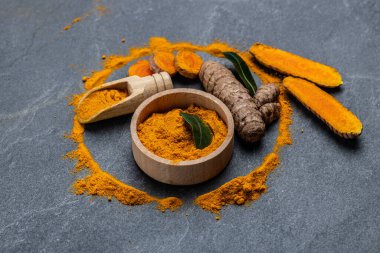 Zerdeçal tozu ve taze zerdeçal. Beton arka planda sokağa çıkma yasağı veya kömür tabakası. Baharat, doğal renklendirme, alternatif tıp. Uzun afiş biçimi. en üstteki görünüm.