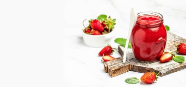 Beyaz arka planda bir kavanoz çilek reçeli. Ev yapımı çilekli marmelat ve meyve. Uzun pankart biçimi.