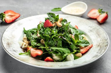 Ispanaklı, fındıklı, peynirli çilekli salata gri taşlı taze vejetaryen salatası, yemek tarifi geçmişi. Kapat.,