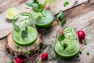 Açık beton arka planda bir bardakta salatalık yeşili smoothie. Detox smoothie, taze bezelye, salatalık, ıspanak ve limon. en üstteki görünüm.