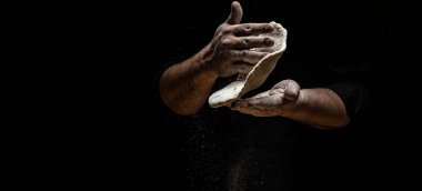 Un dağılmış halde pizza hamuru uçurmak. Siyah üzerine bir un bulutunun dondurucu hareketiyle. Hamur yoğuran elleri pişir. Uzun pankart biçimi, alanı kopyala,
