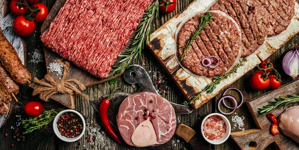 Raw meat products, different parts of the body. minced beef meat kebabs, pork, beef, chicken on a wooden background. Long banner format. top view.