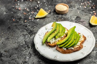 Kahvaltıda sağlıklı avokado tostları ya da öğle yemeğinde çavdar ekmeği, dilimlenmiş avokado, balkabağı tohumu, tuz ve biber. Vejetaryen yemeği. Bitki temelli diyet. Temiz yemek. Üst Manzara. Boşluğu kopyala,