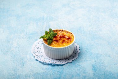 Fransız kremalı Brulee tabakta, geleneksel Fransız vanilyalı tatlı üzerine karamelize şeker ve mavi arka plan.,