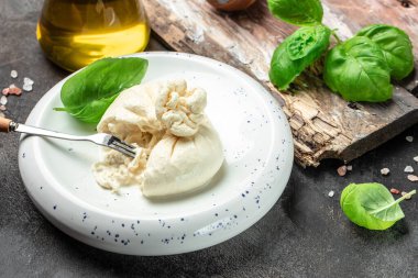 Basil yapraklı burrata peyniri beyaz tabakta koyu arkaplanda. afiş, menü, metin için tarif yeri, üst görünüm.
