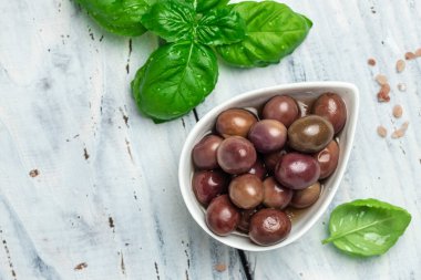 Gri arka planda küçük bir kasede taze biberiyeli pembe zeytinler. Uzun afiş biçimi. en üstteki görünüm.