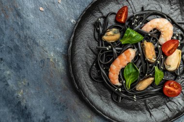 Karidesli ve midyeli siyah spagetti tabağı. Karanlık arka planda. Siyah spagetti. Uzun afiş biçimi. en üstteki görünüm.