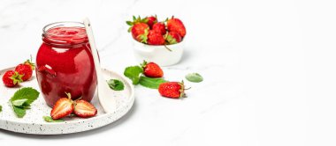 Beyaz arka planda bir kavanoz çilek reçeli. Ev yapımı çilekli marmelat ve meyve. Uzun pankart biçimi.