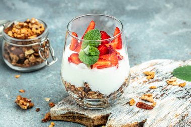 Taze meyveli parfe, Yunan yoğurdu, yulaf ezmesi, bal ve nane yaprakları ahşap bir tahtanın üzerinde cam kavanozda. Glütensiz diyet, sağlıklı kahvaltı. metin için yer, üst görünüm,