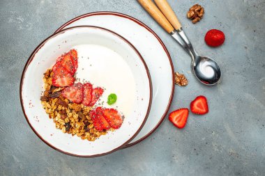 Yoğurtla yoğurt, taze çilek, chia tohumu ve gri arka planda bal. Lezzetli dengeli gıda konsepti. afiş, menü, metin için tarif yeri, üst görünüm.