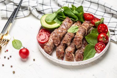 chevapchichi veya Kofta kebabı, domuz pastırması ıspanak, avokado ve kiraz domatesi ile doğranmış et, sağlıklı yağ, kilo vermek için temiz yemek. Keto paleo diyet menüsü, üst görünüm,