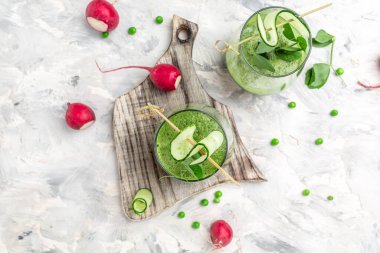 Açık beton arka planda bir bardakta salatalık yeşili smoothie. Detox smoothie, taze bezelye, salatalık, ıspanak ve limon. en üstteki görünüm.