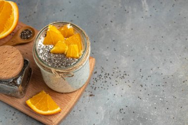 Narenciye ile süslenmiş camda laktozsuz yoğurt ile Chia Seed. Gri arka planda chia tohumlu yoğurt. sağlıklı süper yiyecekler. Sağlıklı yiyecekler. metin için yer.