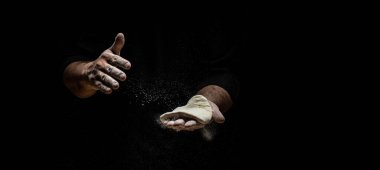 Güzel ve güçlü erkeklerin elleri hamuru yoğurarak ekmek, makarna ya da pizza yaparlar. Bir un bulutu toz gibi uçuşuyor. Yiyecek konsepti.