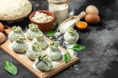 Peynirli ve ıspanaklı Khinkali. Çiğ, yarı bitmiş meyveli börekler. Khinkali pişirmek. Ulusal Gürcü mutfağı. afiş, menü, metin için tarif yeri, üst görünüm.