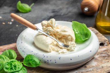 Basil yapraklı burrata peyniri beyaz tabakta koyu arkaplanda. afiş, menü, metin için tarif yeri, üst görünüm.