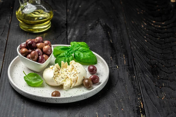 Beyaz tabakta fesleğenli ve zeytinyağlı kremalı İtalyan Burrata peyniri. İtalyan Akdeniz mutfağı. afiş, menü, metin için tarif yeri, üst görünüm.
