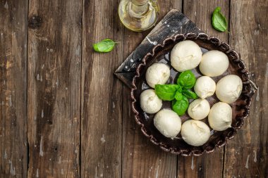 Peynir koleksiyonu, ahşap arka planda taze fesleğen yapraklı yumuşak İtalyan peynirli mozzarella topları. Uzun afiş biçimi. en üstteki görünüm.