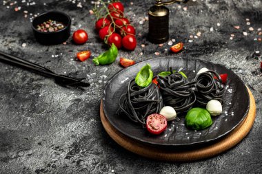 Mürekkep balığı mürekkebi ve yeşil fesleğen yapraklı siyah makarna. Kalamar mürekkepli, keçi buğdaylı makarna. Vejetaryen ya da glütensiz diyet. Restoran menüsü, diyet, yemek kitabı tarifi üst görünümü.