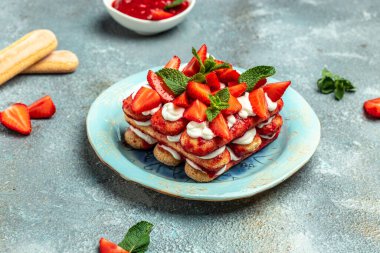 İtalyan tatlı tiramisu keki taze çilek, bisküvi ve krem şanti ile koyu bir arka planda vegan laktozsuz tatlı..