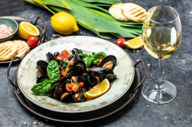 Kil kasede midyeler, bir bardak beyaz şarap ve mavi arka planda limon. Akdeniz mutfağı. Restoran menüsü, diyet, yemek kitabı tarifi üst görünümü.