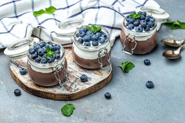 Delicious chocolate mousse or pudding with whipped cream. Chocolate panna cotta with blueberries. Chocolate pudding and greek yogurt parfait.