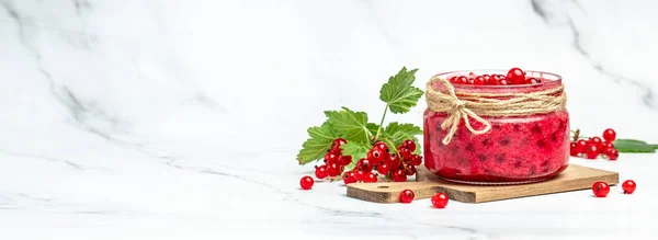 red currant jam in jar. Canned fresh berries on a light background. Long banner format.