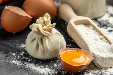 Tahtada et olan çiğ Khinkali. Yarı bitmiş hamur köfteleri karanlık bir arka planda khinkali pişiriyor. Gürcistan hamur tatlısı.