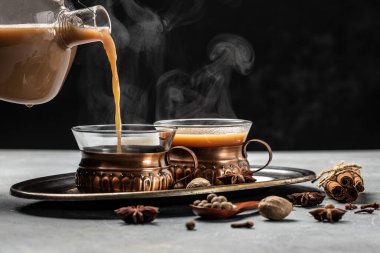 İki kupa Masala çayı. Koyu arkaplanda cam bardakta süt ve baharatlı sıcak Hint masala çayı. metin için yer.