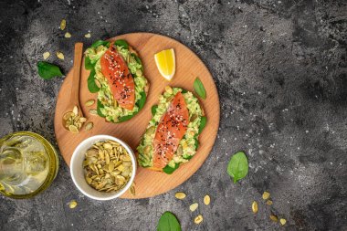 Lezzetli kahvaltı ya da somon balığı, avokado, ıspanak, fındık, ayçekirdeği, kırmızı balık ve guacamole ile tost. Sağlıklı, temiz yemek. Vejetaryen ya da glütensiz diyet. Üst görünüm, boşluk kopyala.