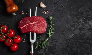 Biberiyeli çatallı çiğ biftek ve arka planda baharatlar. Taze biftek hazırlıyorum. Üst Manzara. metin için yer.