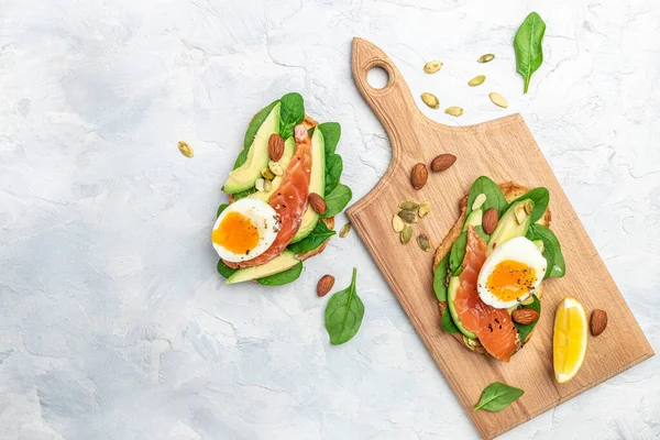 toast with avocadoo, salmon and spinach, nuts, sunflower seeds. Healthy, clean eating. Vegan or gluten free diet. Long banner format. top view.