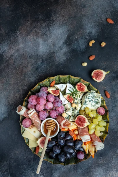 Appetizers table with italian antipasti snacks and wine in glasses. cheese, ham, nuts, fruit, bread sticks. Delicious balanced food concept.